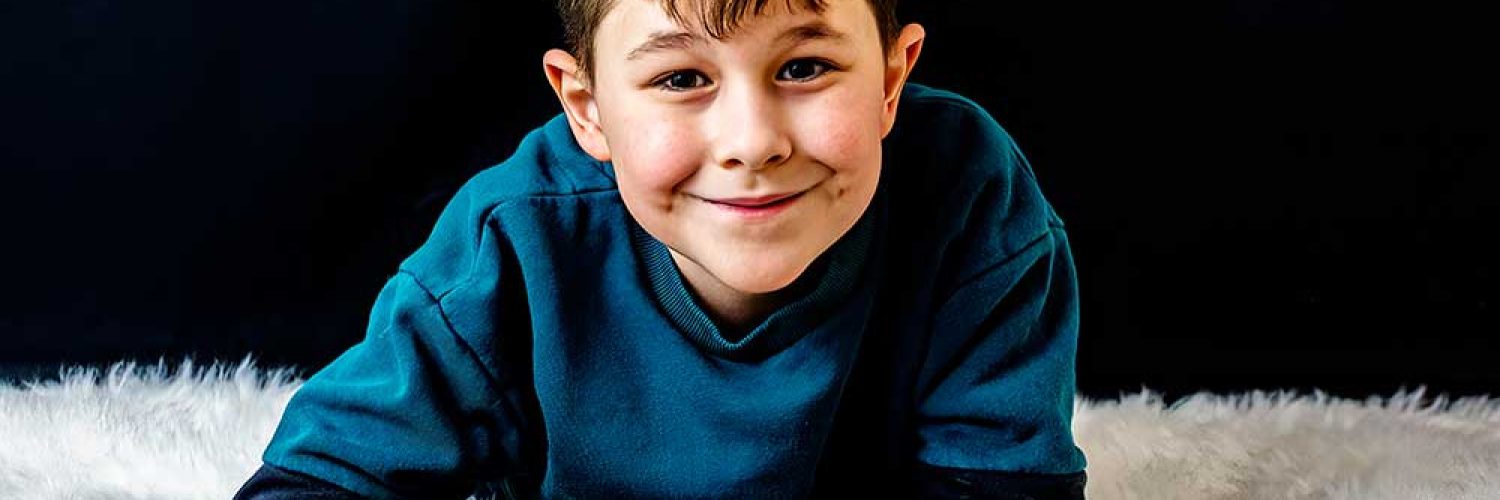 Young boy laying on a rug facing forward. Photographer in Leicester